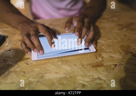 Cropped hands of man using digital tablet at wooden table in cafe Stock Photo