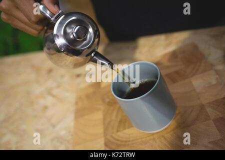 Cropped hand of owner making coffee at bar counter in cafe Stock Photo