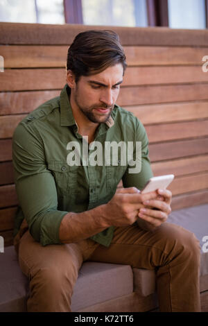 Young man using mobile phone in cottage Stock Photo