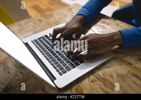 Cropped hands of man using laptop at table in cafe Stock Photo