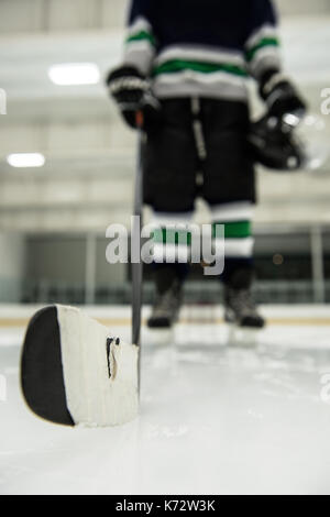 Low section of male player holding ice hockey stick at rink Stock Photo