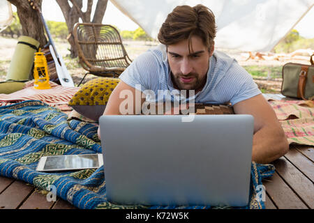 Relaxed young man using laptop in tent Stock Photo