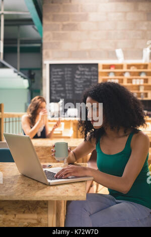Woman using laptop while having cup of coffee in cafÃƒÂ© Stock Photo