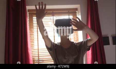 Young woman gesturing while using virtual reality headset at home Stock Photo