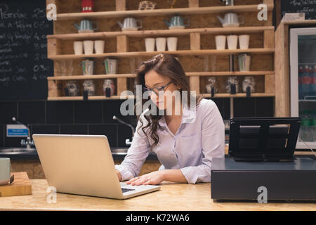Owner using laptop at counter in cafÃƒÂ© Stock Photo