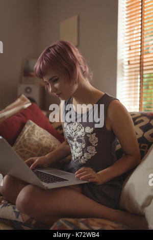 Young woman using laptop on sofa at home Stock Photo