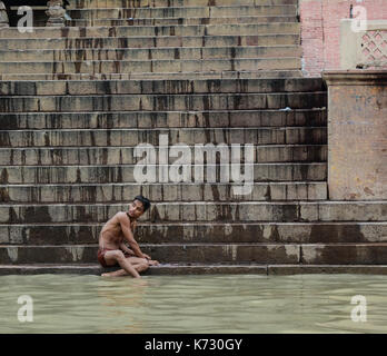 Varanasi, India - Jul 12, 2015. A young man bathing on the Ganges River in Varanasi, India. Varanasi, also known as Kashi and Benaras, is the cultural Stock Photo