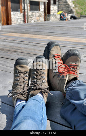 feet of a coupe in hiking shies on wooden terrace Stock Photo