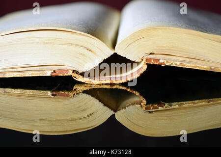 Open old thick book on black reflective table. Horizontal image. Stock Photo