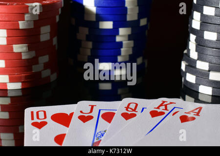 Poker hand royal flush on black reflective board. Poker chips on background. Stock Photo