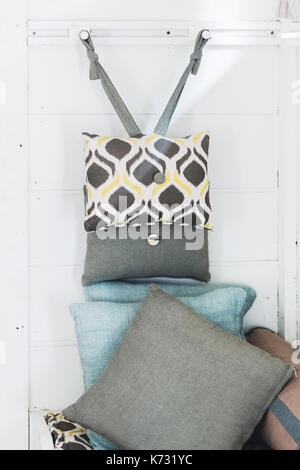 Decorative different grey pillows as decoration of house on wooden wall background Stock Photo