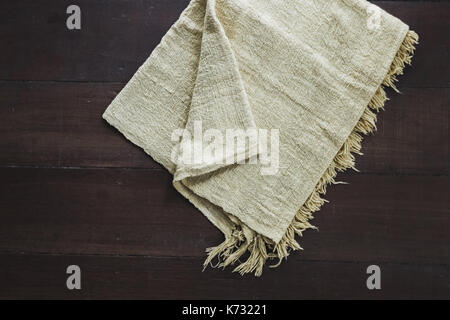 Beige carpet with fringe on dark wooden floor, texture close up Stock Photo