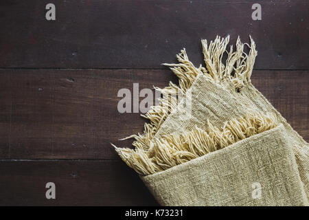 Beige carpet with fringe on dark wooden floor, texture close up Stock Photo