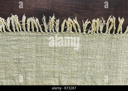 Beige carpet with fringe on dark wooden floor, texture close up Stock Photo