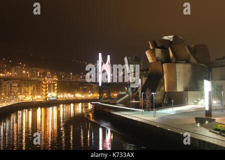 The Guggenheim Museum, Bilbao at night with the city lit up behind it. Stock Photo