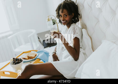 Smiling african american woman having a relaxing breakfast in bed at home Stock Photo