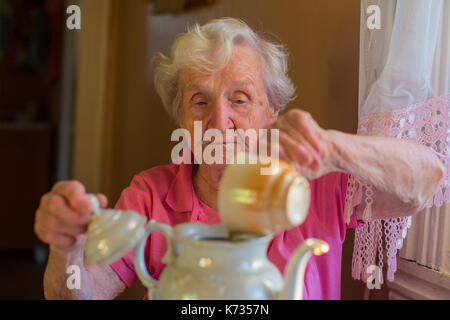 Elderly woman making tea in the kettle. Stock Photo