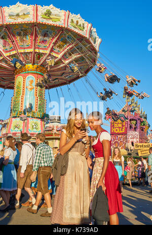 two girls in traditional dress taking photos in Octoberfest in Munich, Germany Stock Photo