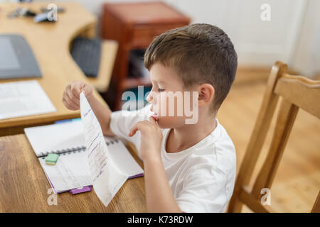 Little schoolboy checking his homework mistakes, thinking Stock Photo