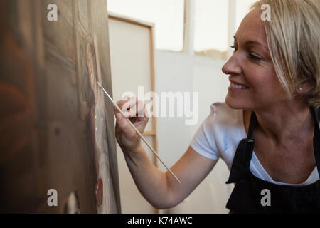 Happy woman painting on canvas in drawing class Stock Photo