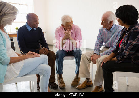 Senior people discussing while sitting on chair in art class Stock Photo