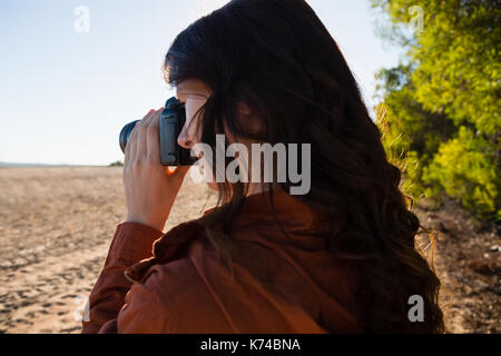 Young woman photographing from camera on field Stock Photo