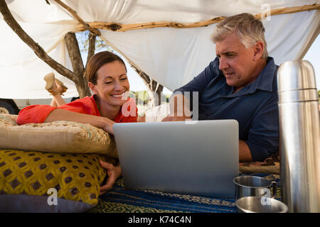 Relaxed couple looking at laptop in tent Stock Photo