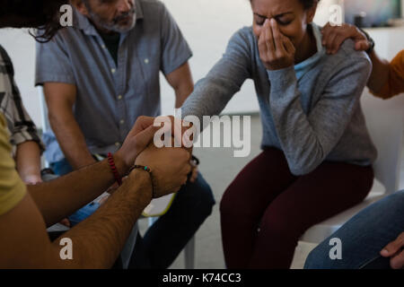 Friends consoling woman while sitting on chair in art class Stock Photo