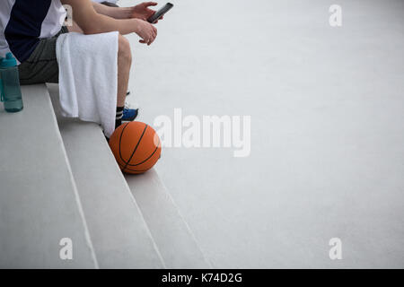 Basketball player using mobile phone on terrace Stock Photo
