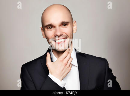 Portrait of smiling man stroking his chin. Headshot on gray background. Stock Photo