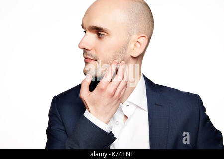 Side view of young man wearing suit. He scratches his chin. Stock Photo