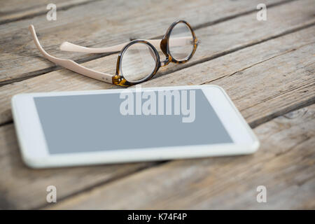 Close up of eyeglasses and tablet computer on wooden table Stock Photo