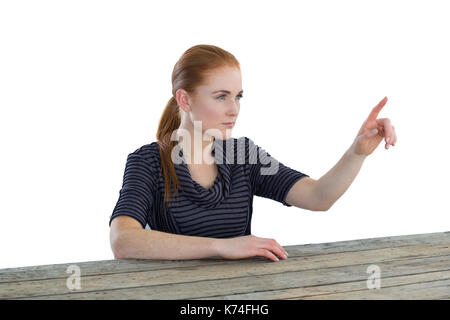 Confident businesswoman using imaginary screen while sitting at table against white background Stock Photo