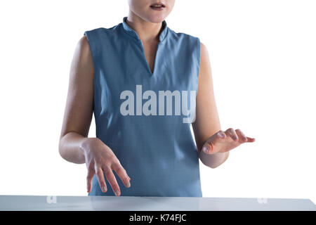 Mid section of businesswoman using imaginary screen at table against white background Stock Photo