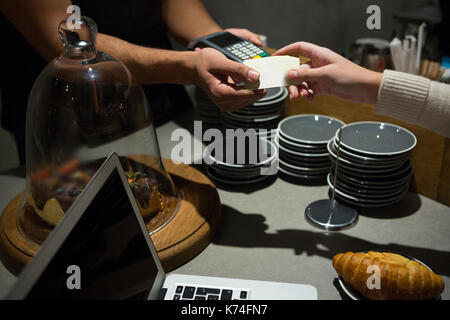 Customer making payment through credit card at counter in restaurant Stock Photo