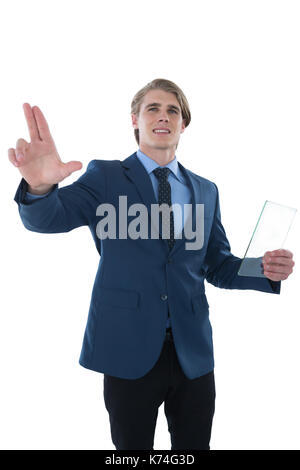Young businessman holding glass interface while touching imaginary screen against white background Stock Photo
