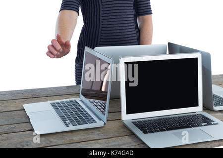 Mid section of businesswoman using interface by laptop computers on table against white background Stock Photo