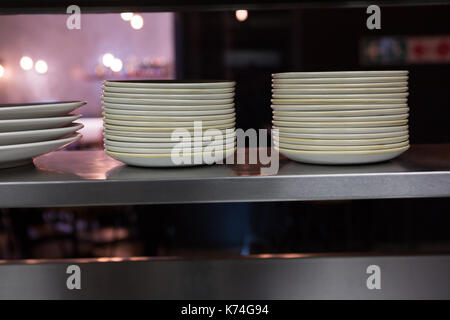 Stack of plates arranged on shelf in restaurant Stock Photo