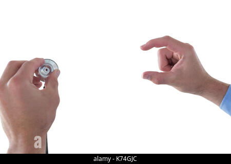 Cropped hand on doctor holding stethoscope while using invisible interface against white background Stock Photo