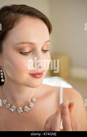 Close up of beautiful bride looking wedding ring while sitting at home Stock Photo