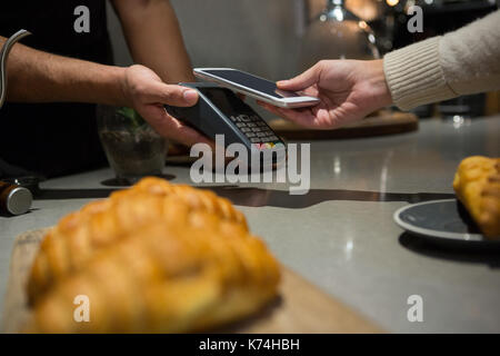 Woman paying bill through smartphone using NFC technology in restaurant