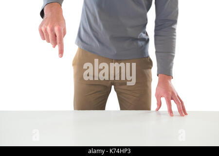 Mid section of creative businessman gesturing while standing at table against white background Stock Photo