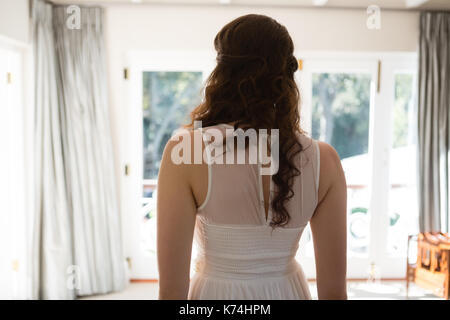 Rear view of bride in wedding dress standing at home Stock Photo