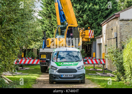 A large crane lorry and car parked in a back lane, on hire to lift heavy construction materials into a nearby garden. Lincolnshire, England, UK. Stock Photo