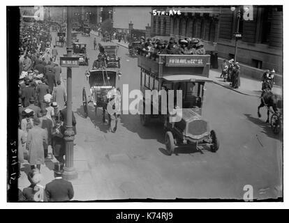 View, looking north, of the corner of West 51st street and 5th Avenue, showing crowded streets with pedestrians and automobile traffic, New York City, circa 1915. Horse-drawn carriages and cars share the road. Stock Photo