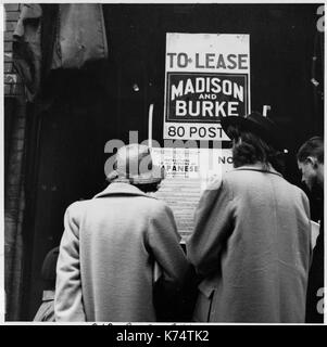 Shoppers reading the order directing evacuation of persons of Japanese ancestry posted on a store window on Grant Avenue in Chinatown, San Francisco, CA, 04/17/1942. Photo by Dorothea Lange Stock Photo