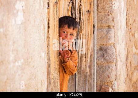 Happy young Bolivian boy in doorway waving in the town Tarabuco, Yamparáez Province, Bolivia Stock Photo