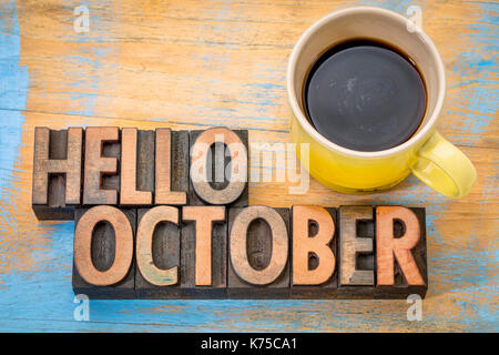 hello October greeting card - vintage letterpress wood type blocks against grained wood with a cup of coffee Stock Photo