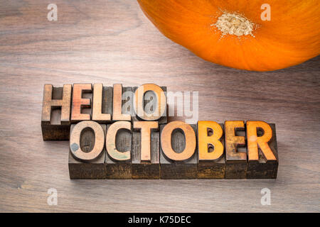 hello October greeting card - letterpress wood type blocks against grained wood with a pumpkin Stock Photo