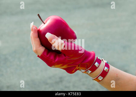 Female hand wearing a red glove holding an apple Stock Photo